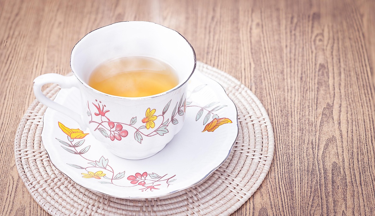Tazza di tè fumante su un tavolo, con limone e foglie di tè, ideale per bruciare grassi addominali.