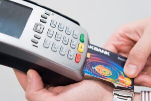 Immagine che illustra il pagamento contactless con una carta e smartphone, evidenziando i rischi associati.
